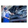 A technician with a long digital torque wrench works on a wheel or axle
