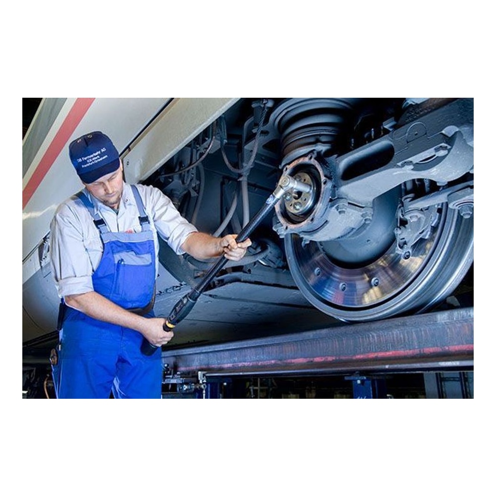 A technician with a long digital torque wrench works on a wheel or axle