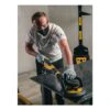 A person uses a yellow-and-black handheld sander on a dark tabletop