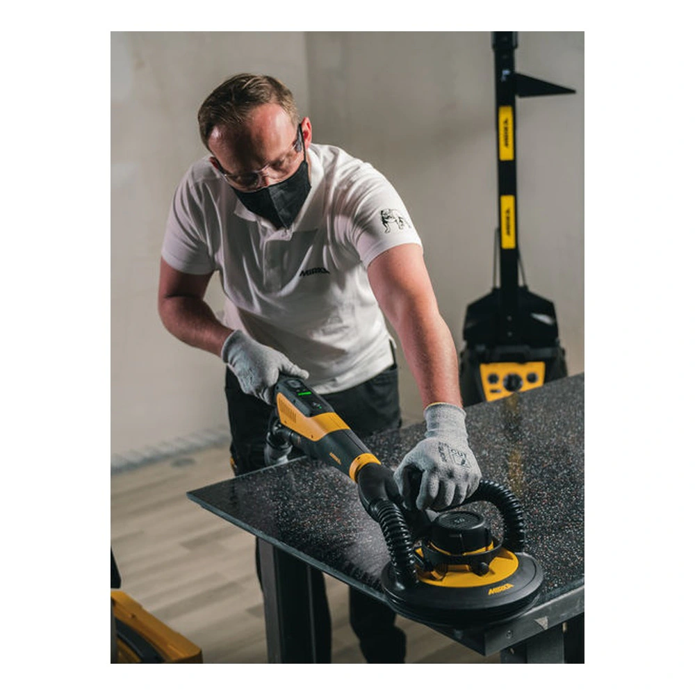 A person uses a yellow-and-black handheld sander on a dark tabletop