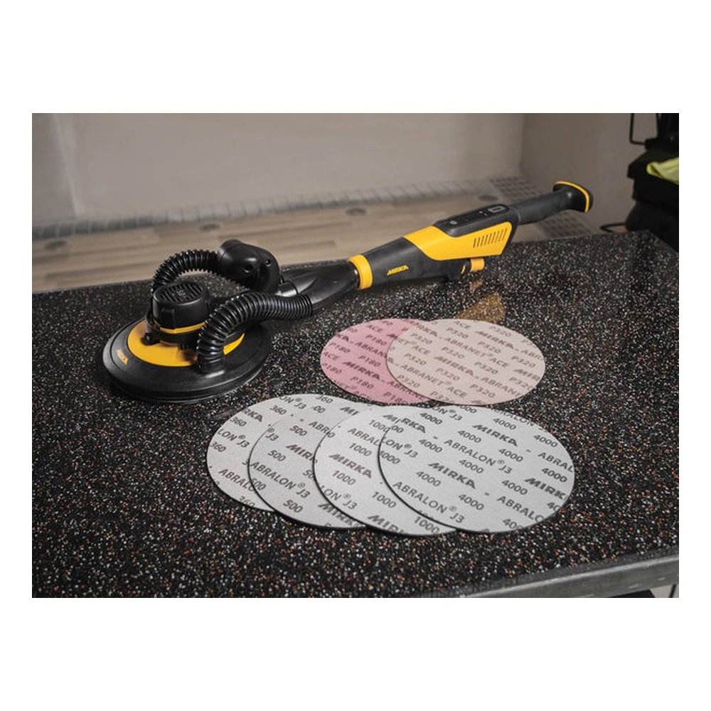 A yellow-and-black handheld sander rests on a dark table, with several round