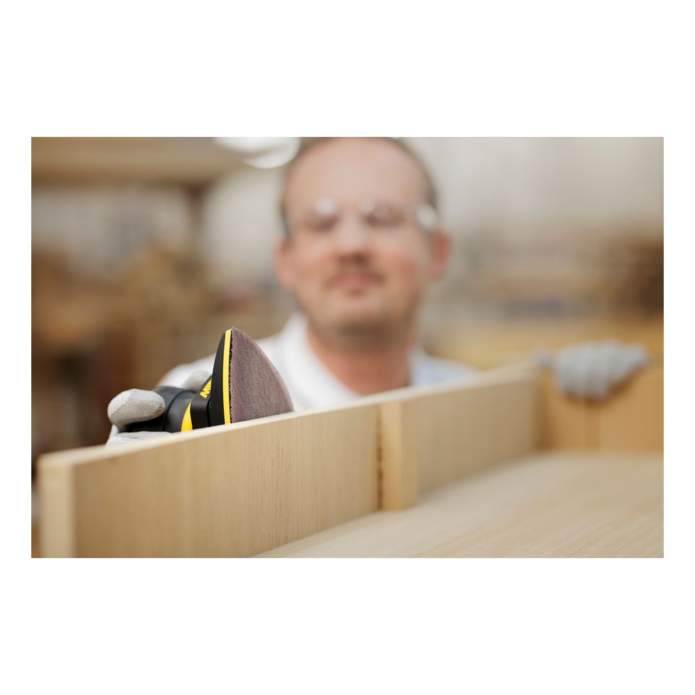 A person holds a sander with a triangular mesh sheet against wood