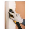 A gloved hand holds a yellow-and-black triangular sander against a wall
