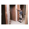 A person uses a yellow hand sander on a wall inside an interior construction