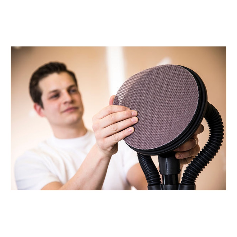 A person is holding and showing a round sanding disc attached to a sander