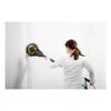 A person is using a yellow and black round wall sander on a white wall