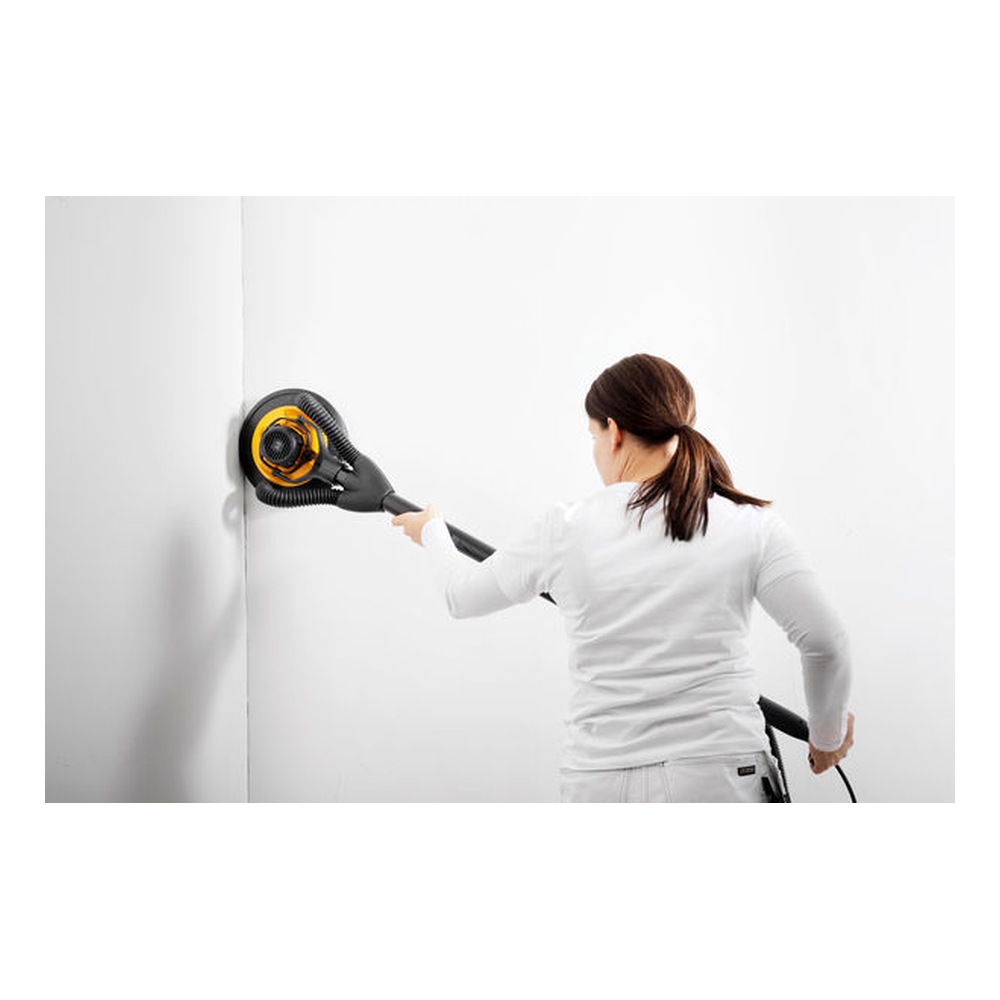 A person is using a yellow and black round wall sander on a white wall