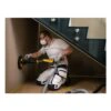 A kneeling person is sanding a wall under a staircase with a round sander