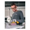A man uses a yellow-and-black power sander on a light-colored metal surface