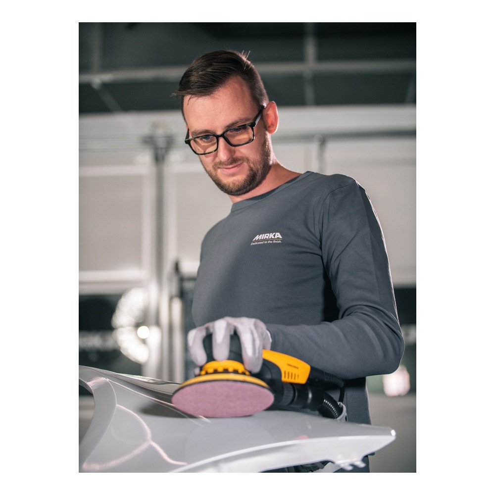 A man uses a yellow-and-black power sander on a light-colored metal surface