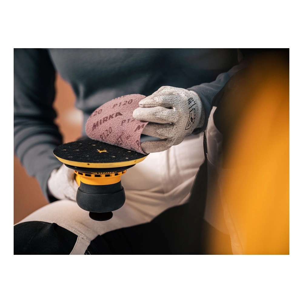 Close-up of a handheld sander with a sanding disc attached, while a gloved