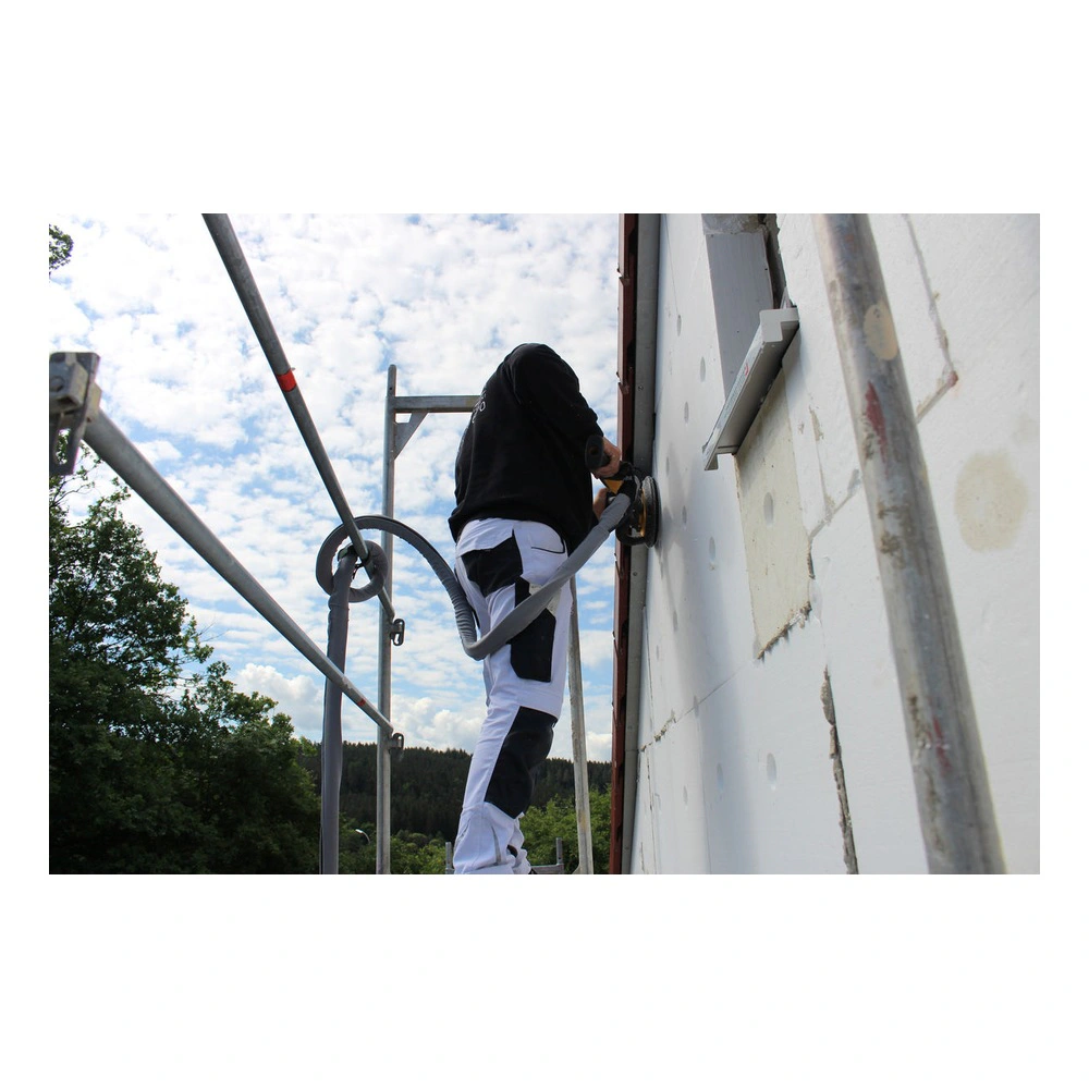 A person working on an exterior wall using a sanding tool, on scaffolding