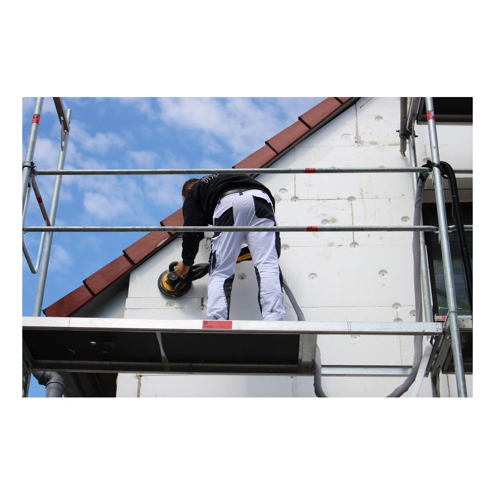 A person sands a white exterior wall from scaffolding, with a round sander