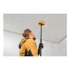 A person using a long pole with a yellow head on a ceiling in a white room