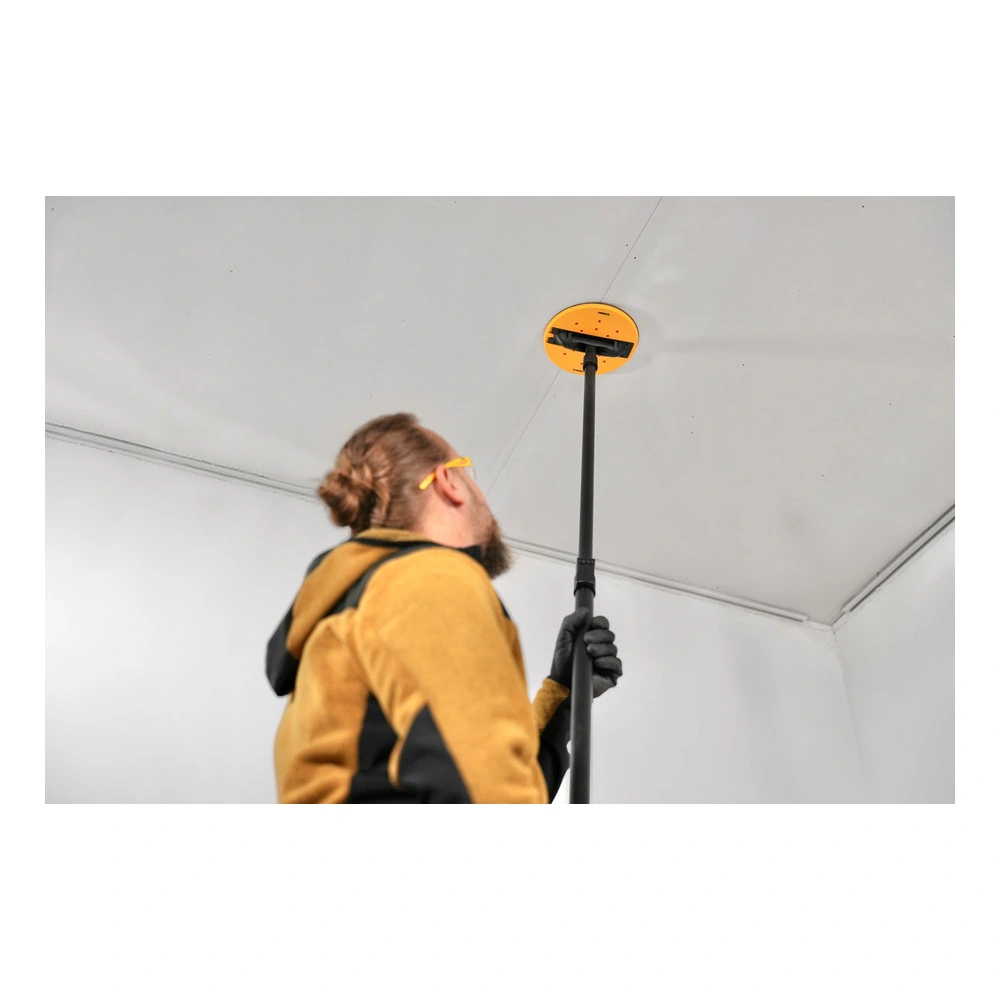 A person using a long pole with a yellow head on a ceiling in a white room