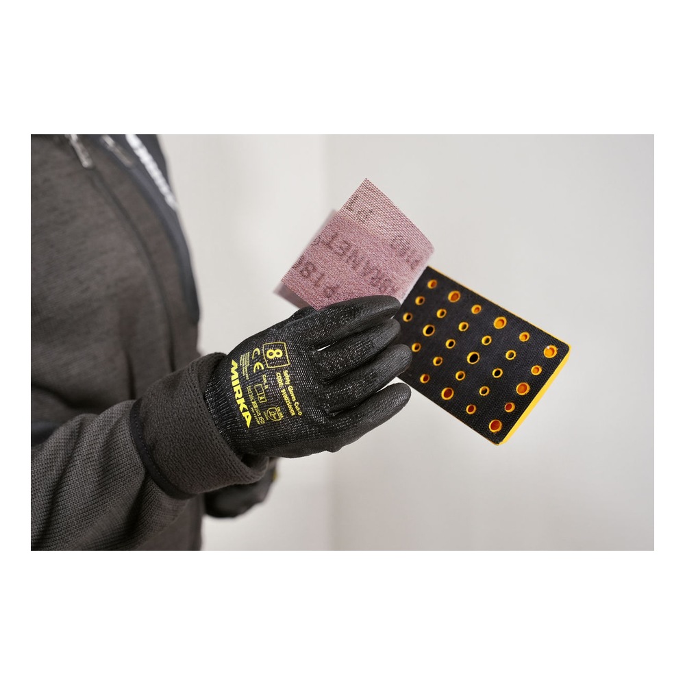 Close-up of a gloved hand holding a sanding sheet and a perforated