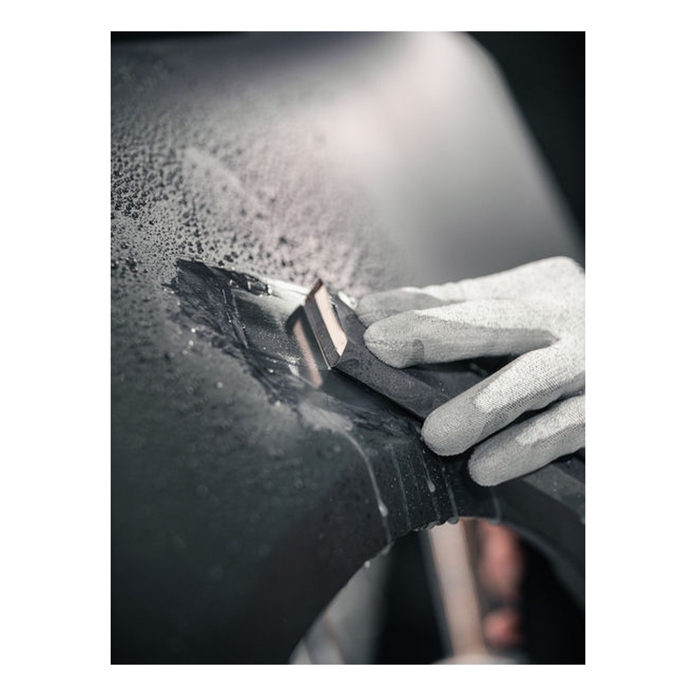 Another close-up of a gloved hand and sanding sheet on a curved black