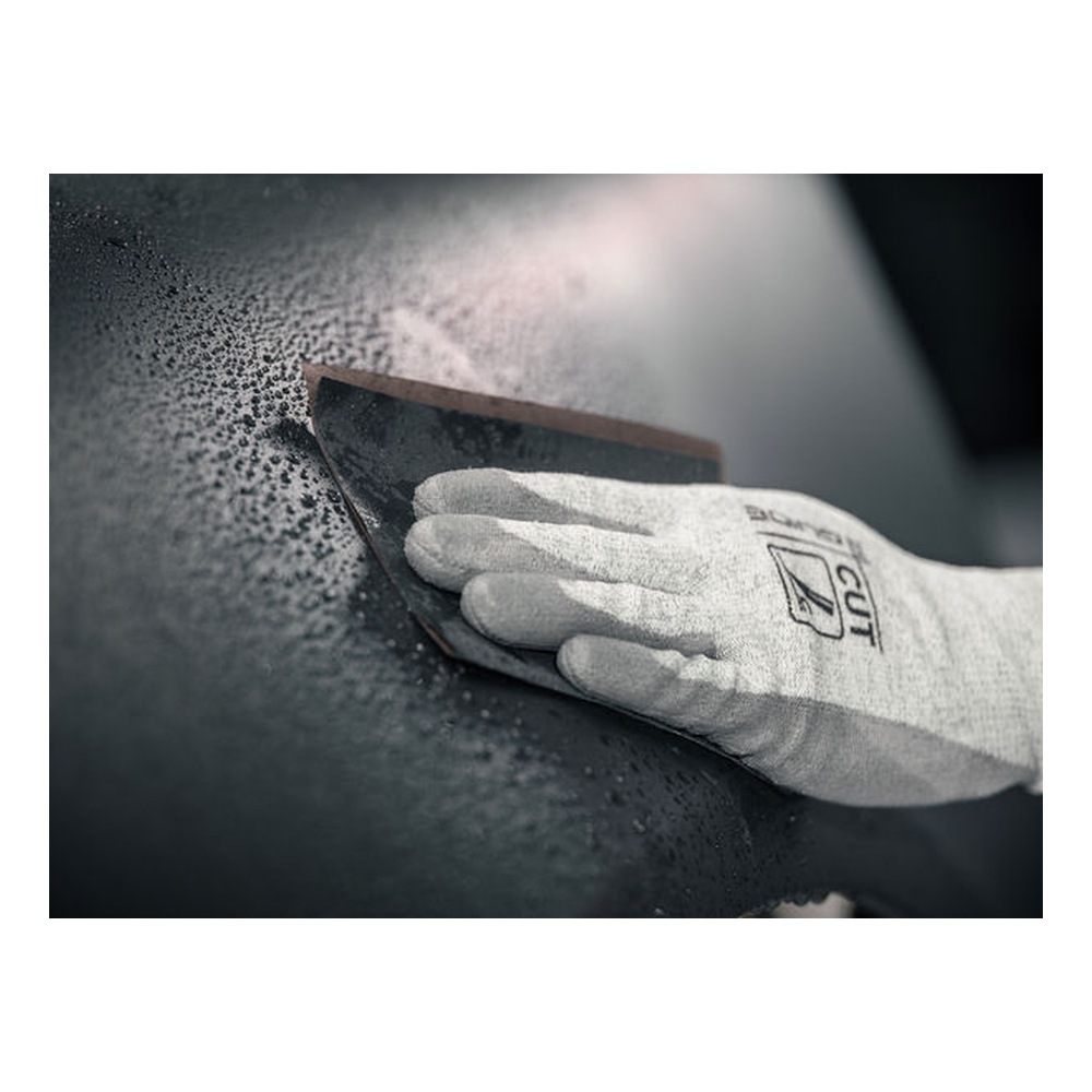 A gloved hand holding a piece of sanding paper against a black surface