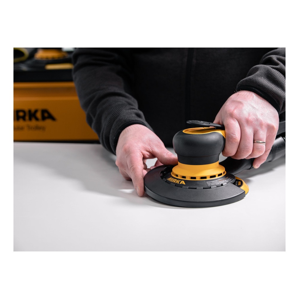 אדם מחזיק מלטשת Mirka צהובה-שחורה עם מגן קצה שחור מורכב, על משטח לבן