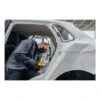 A person working inside a white vehicle body, using a small yellow and black