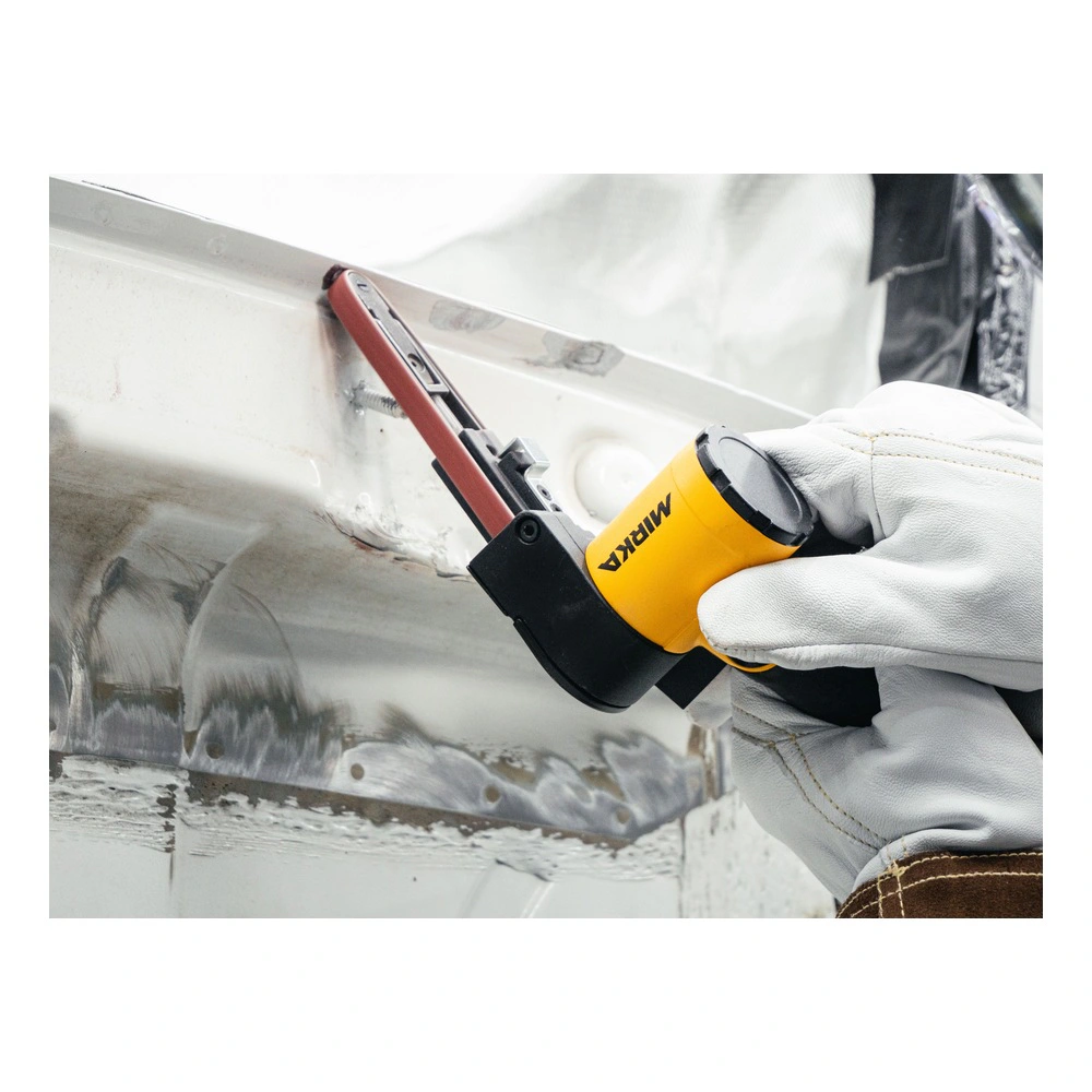A person holds a small yellow and black belt sanding tool against a metal