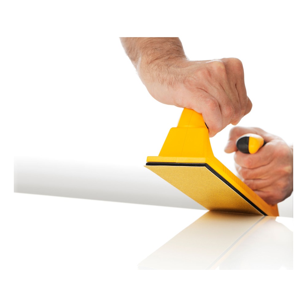 Yellow sanding board with black handles, held by hands in a working position