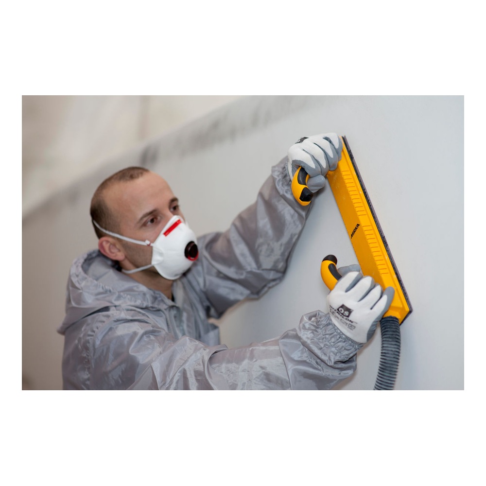A person wearing a protective mask uses a yellow sanding board on a light