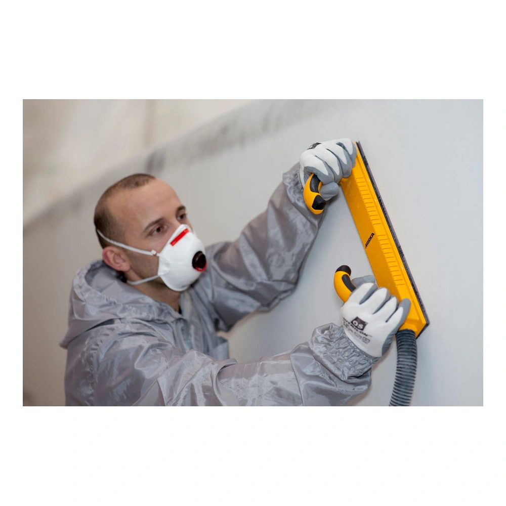 A person wearing a protective mask uses a yellow sanding board on a light