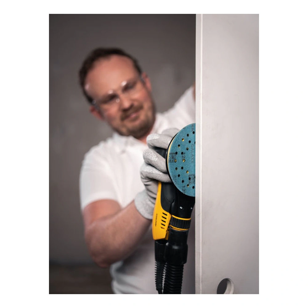 A person uses a round sander against a vertical panel, with a blue
