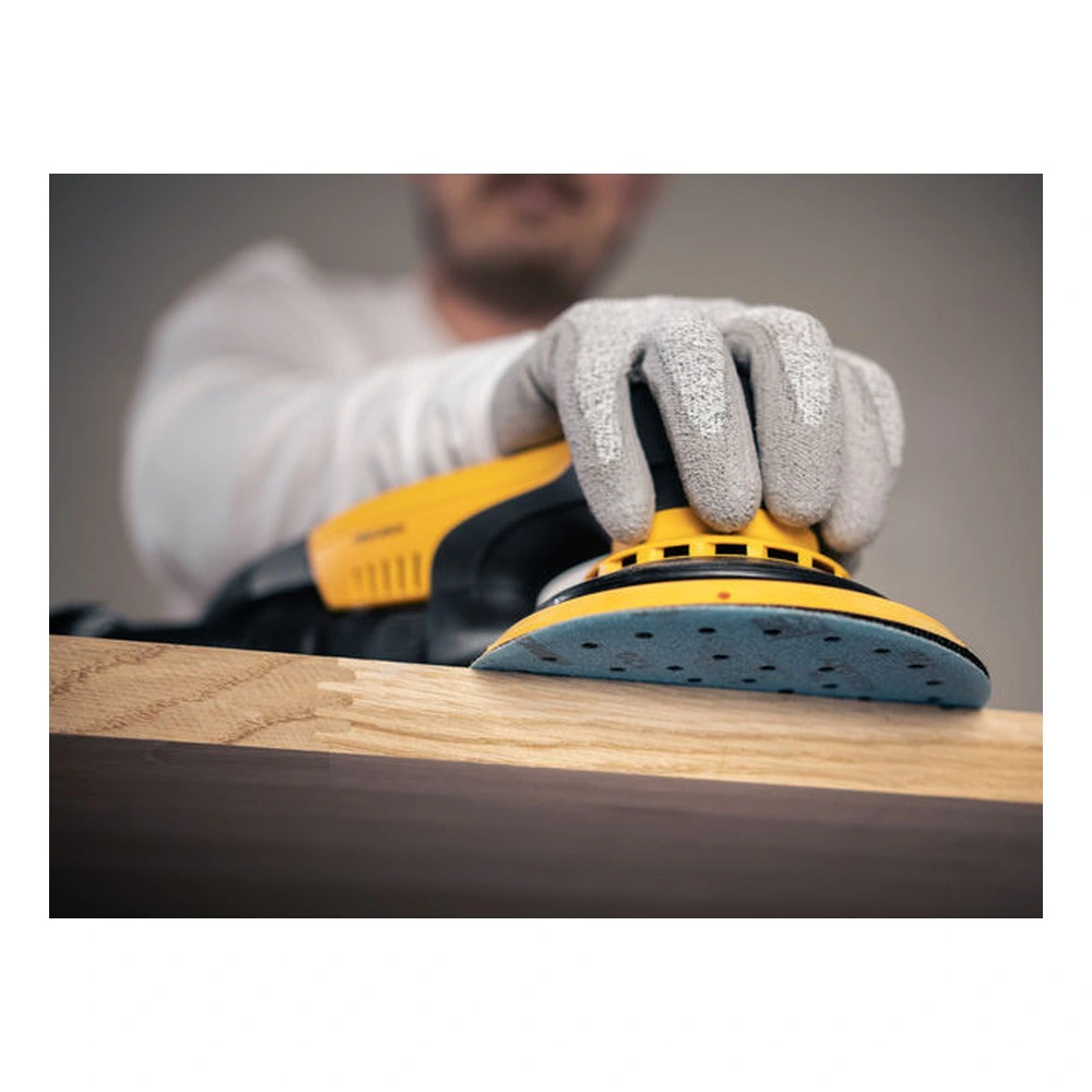 Yellow hand sander on a wooden surface