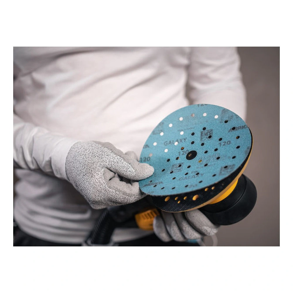 Gloved hands holding a round sander and a light-blue sanding disc above