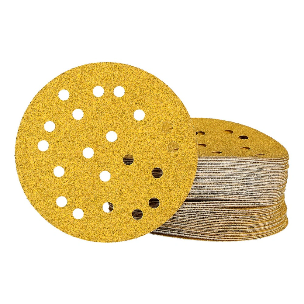 A stack of perforated round yellow sanding discs, with one disc placed
