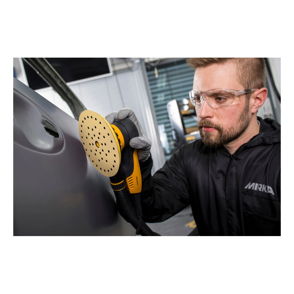 A person uses a yellow and black round sander on a gray car panel, shown