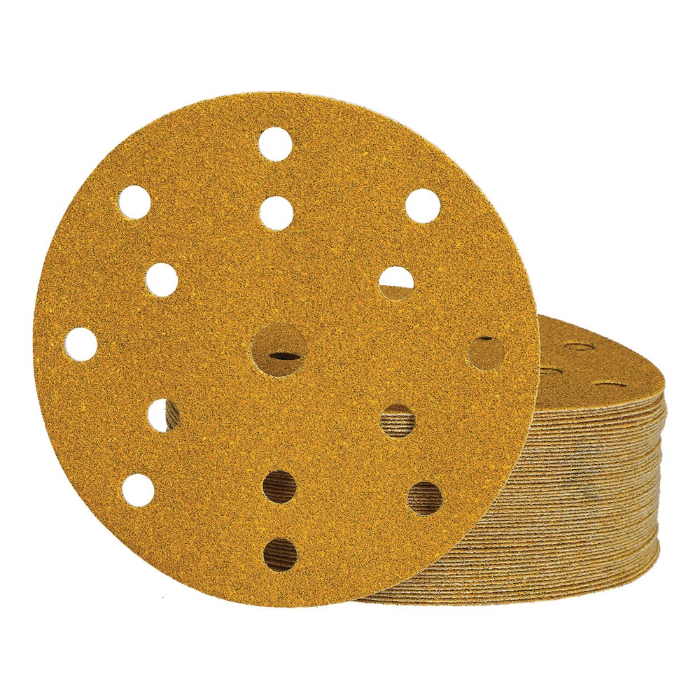 View of a round yellow sanding disc with 15 holes, shown in front of a stack