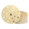 A gold perforated round sanding disc with a stack of discs behind it, front