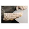 A person wearing gloves applies or sands with a strip of abrasive