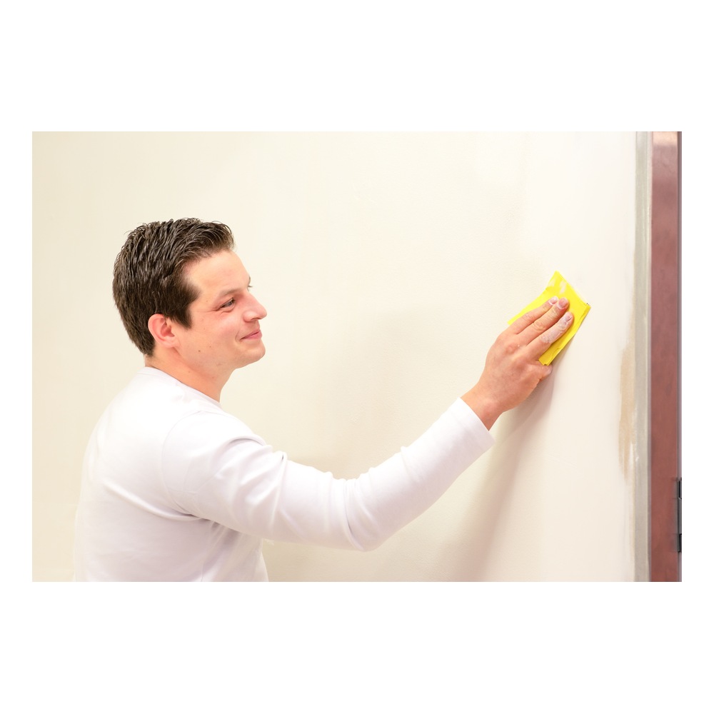 אדם משייף קיר עם נייר שיוף צהוב - Person sanding a wall with yellow sandpaper