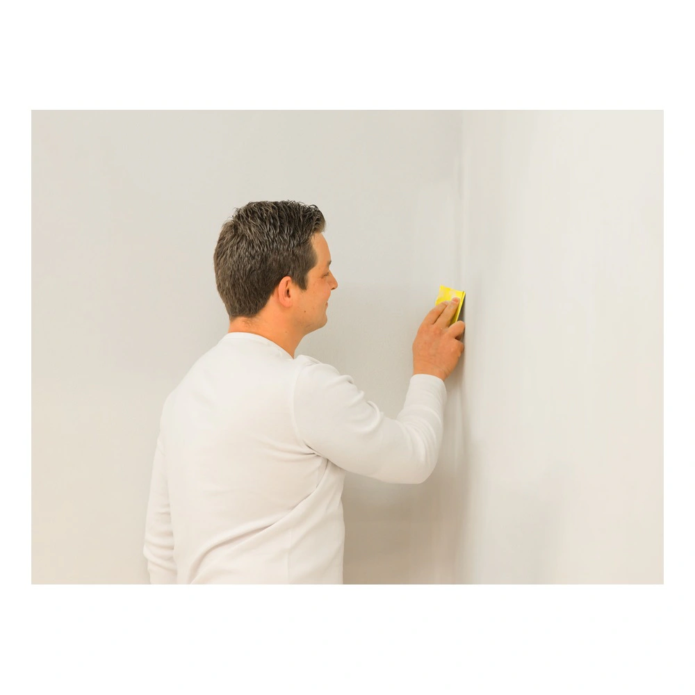 Person sanding a wall with yellow paper