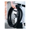 A person holding a coiled black flexible hose, with a white and black work
