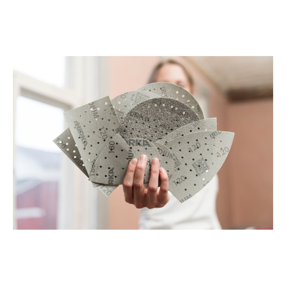 A person holding several perforated sanding discs in a fan-like arrangement