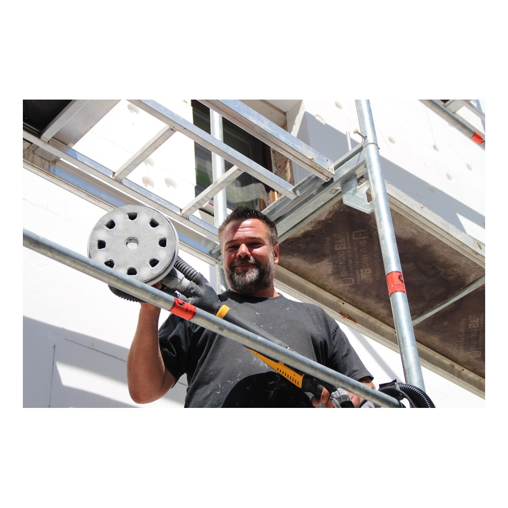 Person using sander on exterior scaffolding