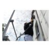 A man on scaffolding sanding an exterior wall surface with a power tool