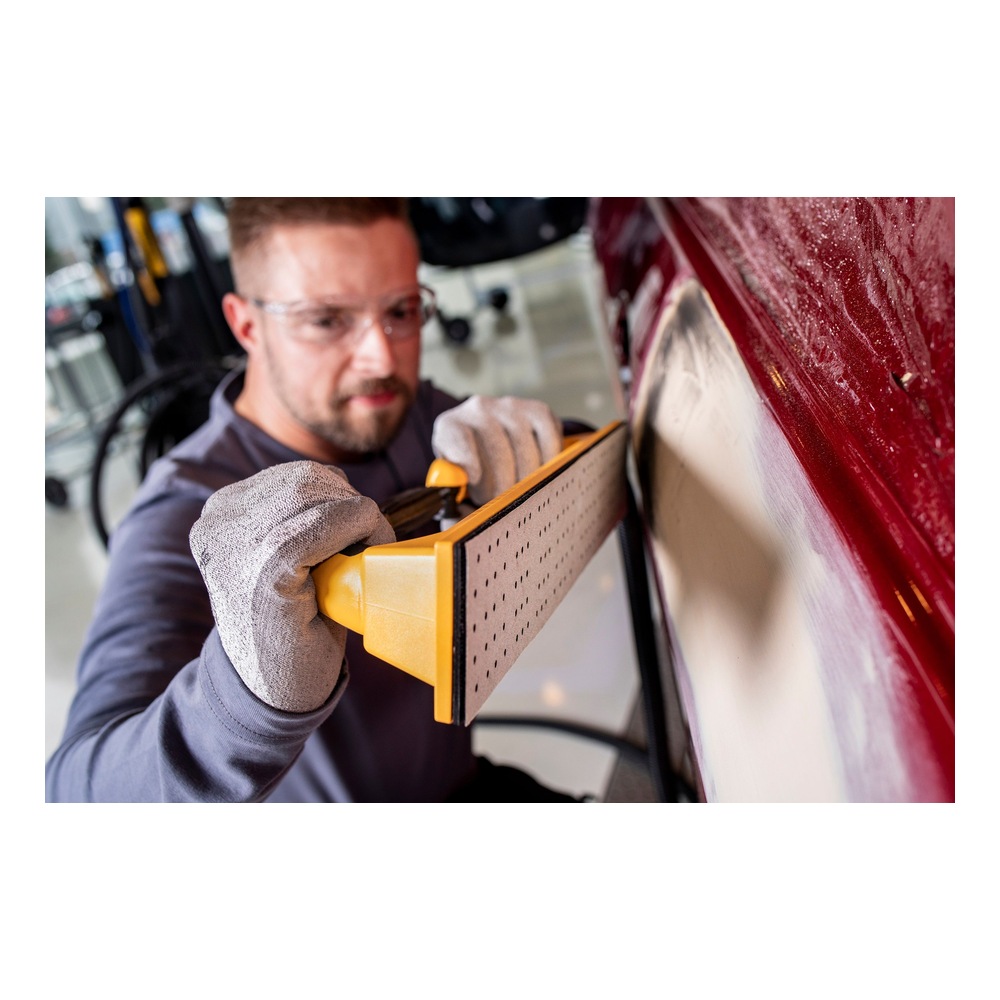 Person using a hand sander on red surface