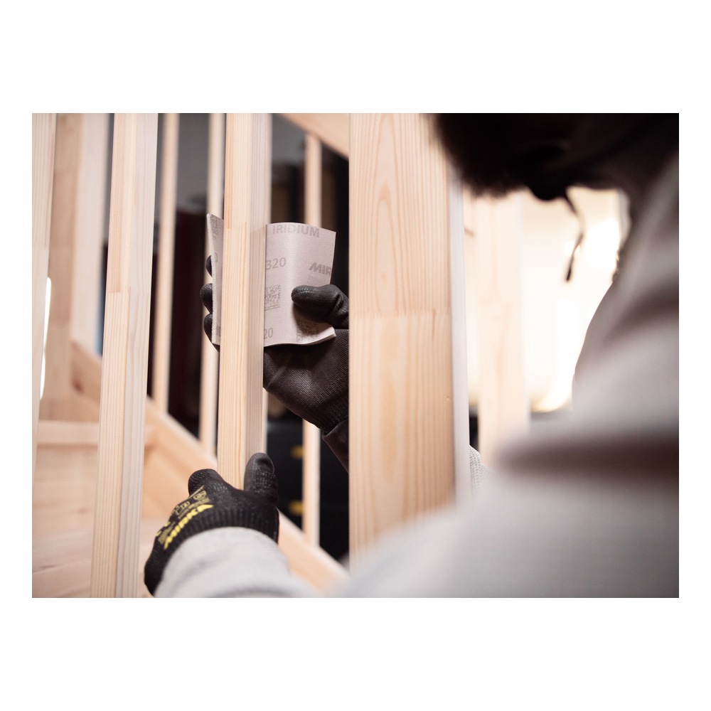 Person sanding wood between slats with sheet
