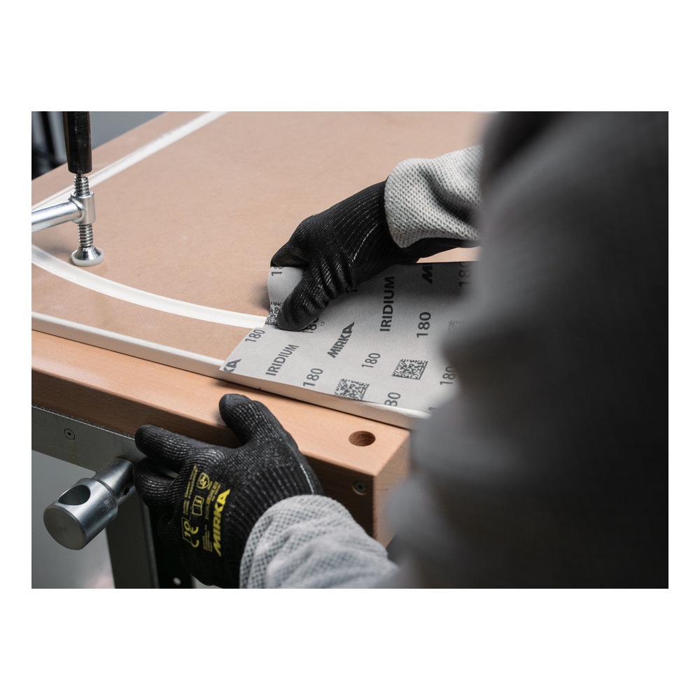 A person presses a sanding sheet onto a wooden surface using a tool, shown