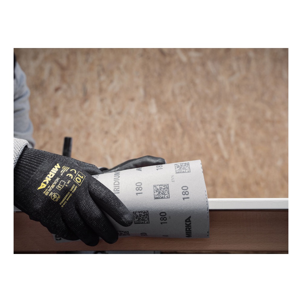 A gloved hand holds a sheet of sanding paper with Mirka markings, against