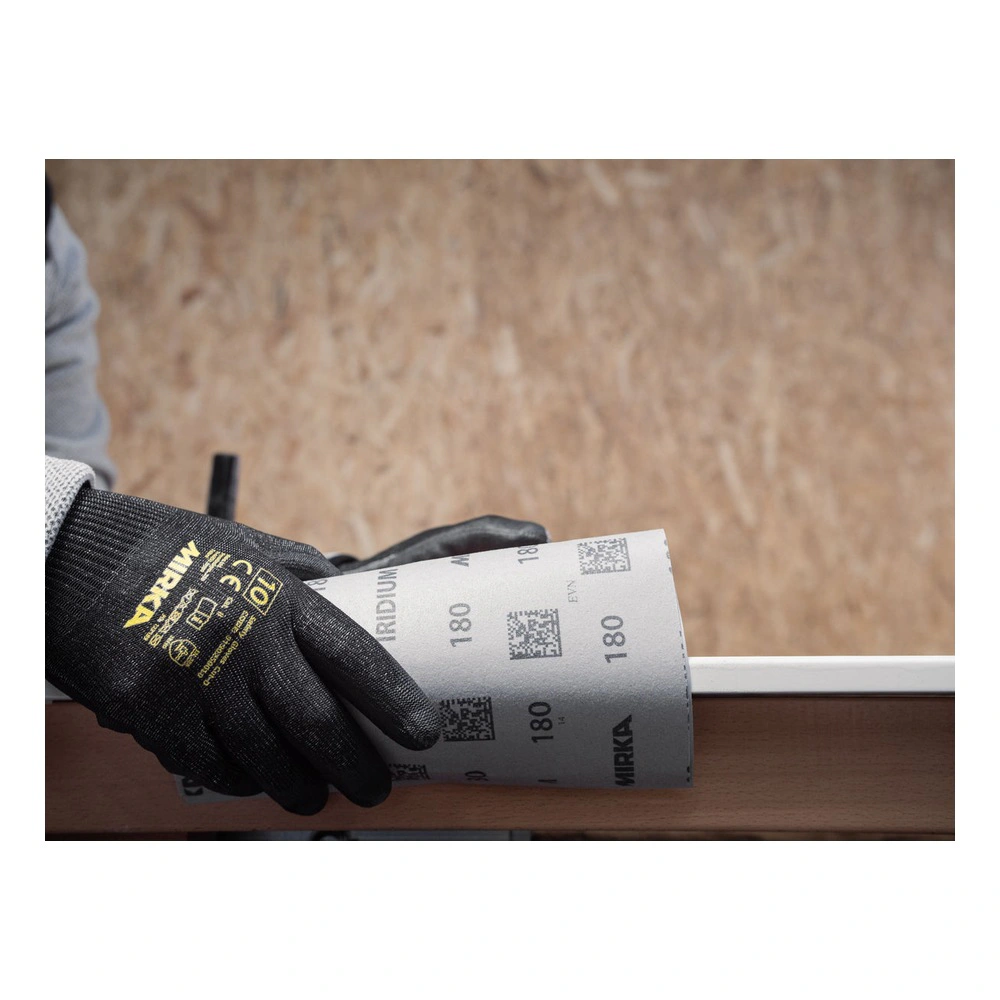 A gloved hand holds a sheet of sanding paper with Mirka markings, against