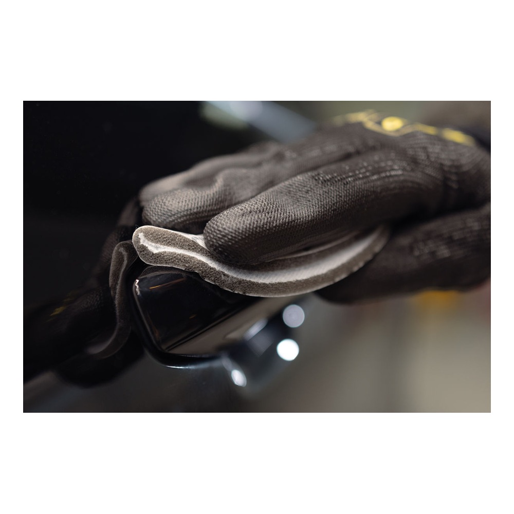 A close application photo of a gloved hand holding a dark curved surface