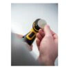 Hands hold a small black and yellow sander with a light-colored round disc