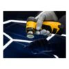 A close view of a yellow and black tool held by a gloved hand over a dark